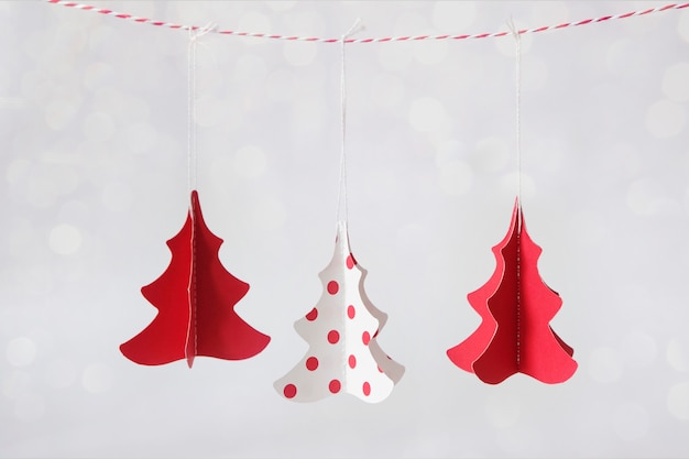 Tres árboles de navidad hechos de papel en rojo y blanco.