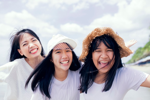 Três asiáticas jovens e adolescentes felizes na praia
