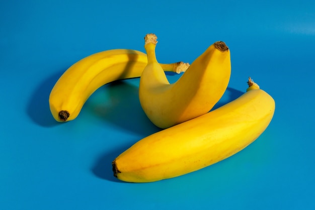Três bananas em fundo azul composição de frutas coloridas de bananas frescas amarelas