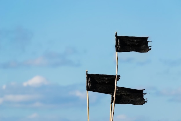 Tres banderas negras bajo un cielo azul