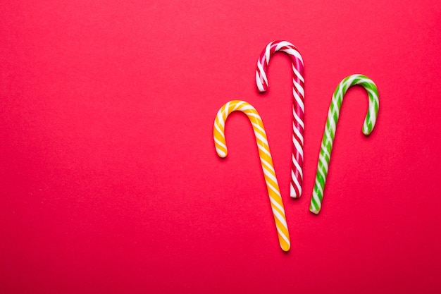 Tres bastones de caramelo de Navidad sobre un fondo rojo.