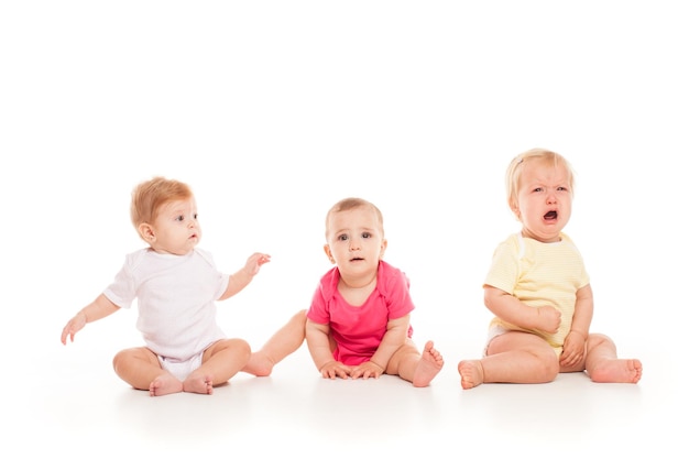 Tres bebés sentados aislados en el blanco