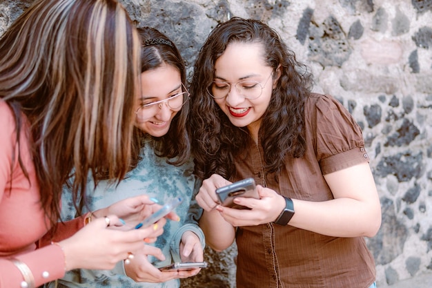 Três belas jovens andam na cidade usando telefone ao ar livre