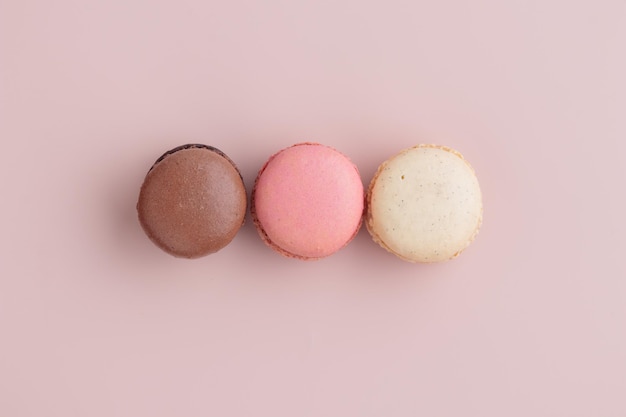Três biscoitos de cor pastel em fundo rosa padrão de biscoitos franceses coloridos Presente para 8 de março Dia Internacional da Mulher Dia dos Namorados
