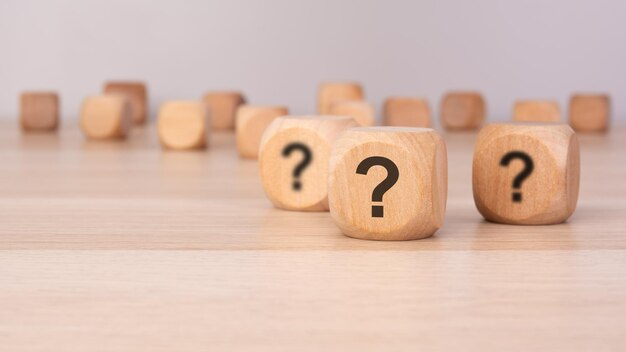 tres bloques de madera con signos de interrogación sobre un fondo gris con espacio de copia