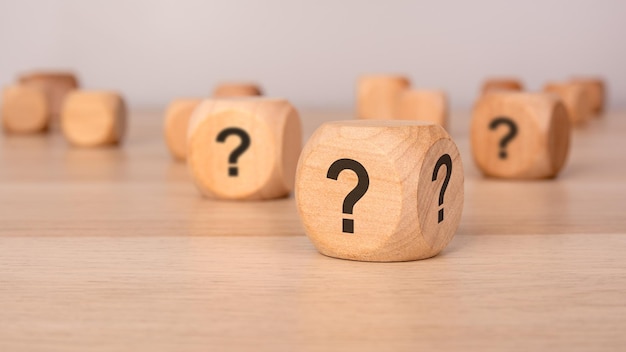 tres bloques de madera con signos de interrogación sobre un fondo gris con espacio de copia