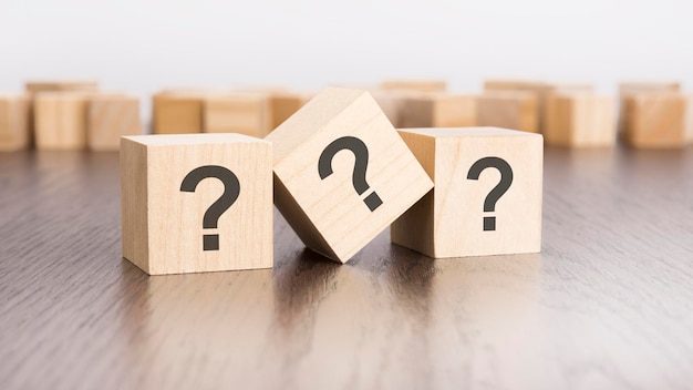 tres bloques de madera con signos de interrogación sobre un fondo gris con espacio para copiar