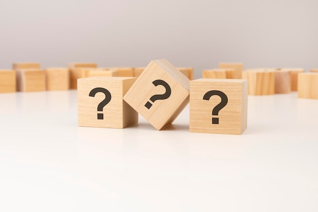 tres bloques de madera con signos de interrogación sobre un fondo gris con espacio para copiar