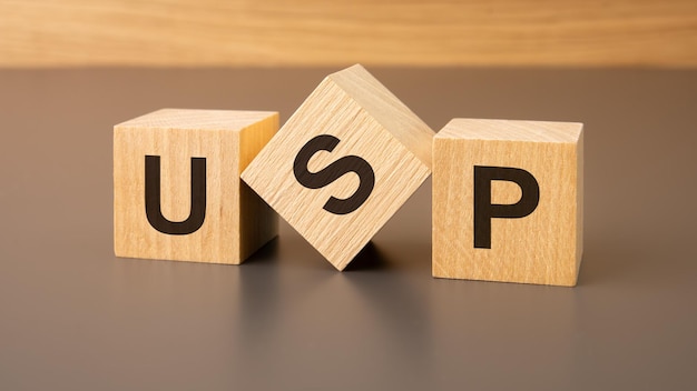 Tres bloques de madera sobre un fondo marrón con la abreviatura USP Unique Selling Proposition