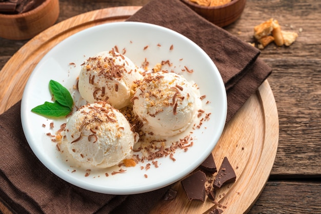 Três bolas de sorvete cremoso com gotas de chocolate e hortelã em uma parede marrom