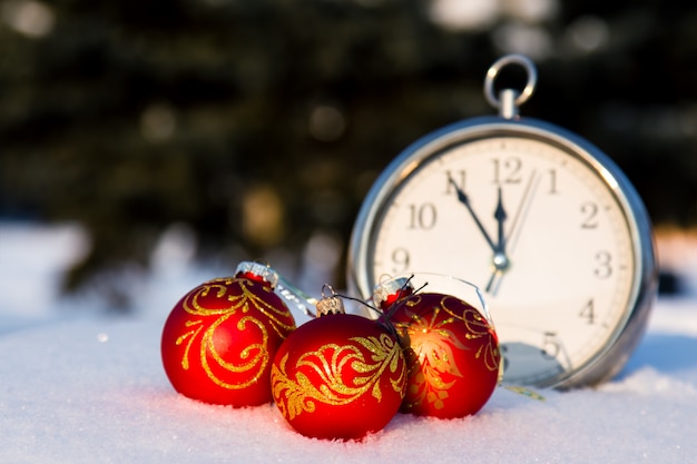 Tres bolas rojas de la Navidad y wath en una nieve.