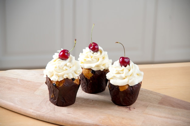 Três bolinhos doces com creme e cereja