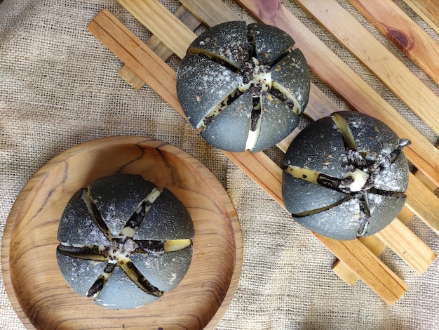 Tres bollos blancos y negros en un plato de madera con una cuchara de madera encima.