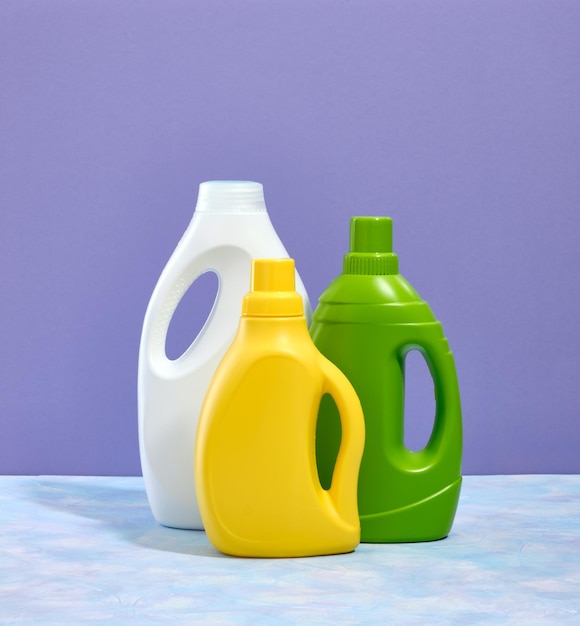 Tres botellas de colores de detergente líquido para ropa en una mesa Un día de lavandería y tareas domésticas