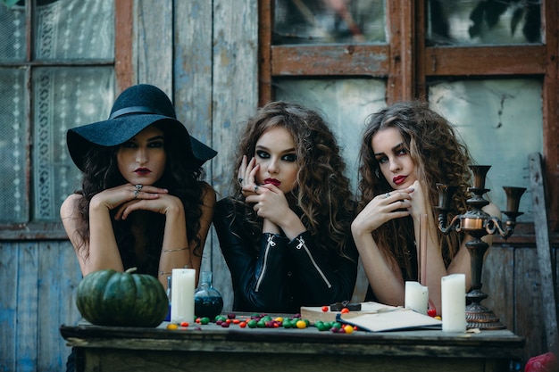 Tres brujas están sentadas en una mesa en vísperas de Halloween