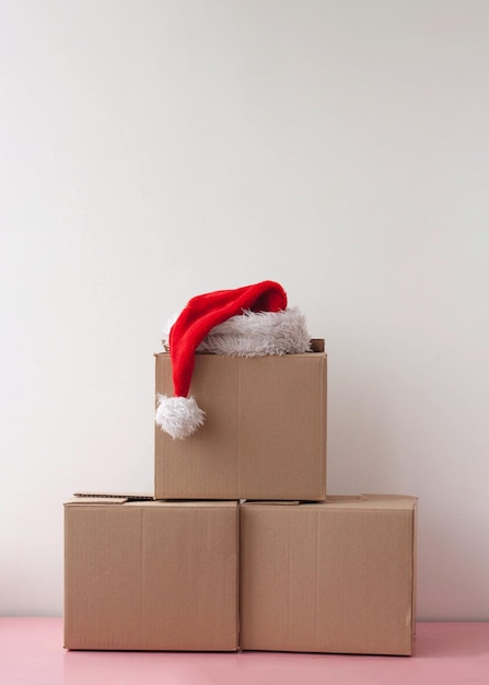 Três caixas de papelão empilhadas uma em cima da outra e um chapéu de papai noel vermelho em cima.