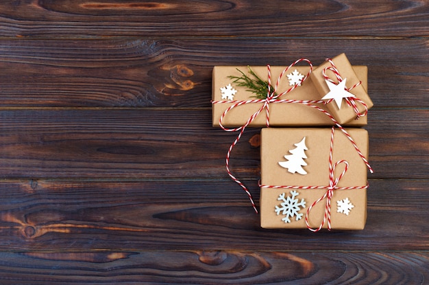 Tres cajas festivas en papel craf decorado con copos de nieve y estrellas en mesa de madera.