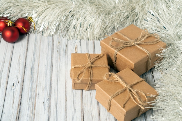 Tres cajas de regalo en una mesa de madera decorada con una guirnalda y bolas rojas de Navidad para el Año Nuevo o Navidad. Concepto de servicio de correo, mensajería o entrega. Copia espacio