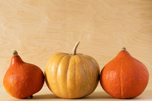 Foto tres calabazas sentadas en una fila sobre fondo de madera amarilla