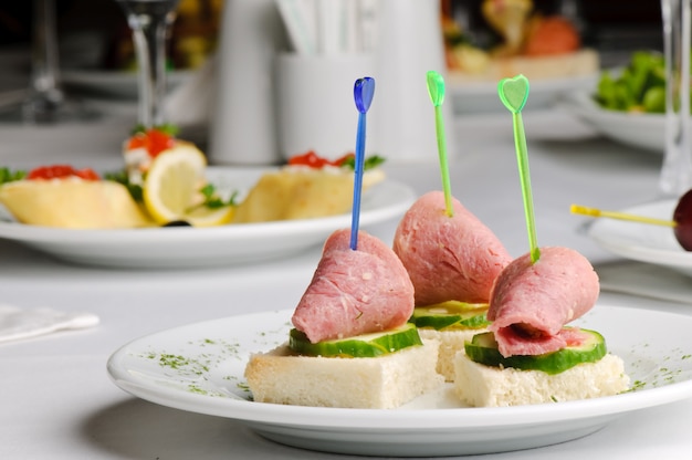 Tres canapés de carne y pepino con palillo de dientes.