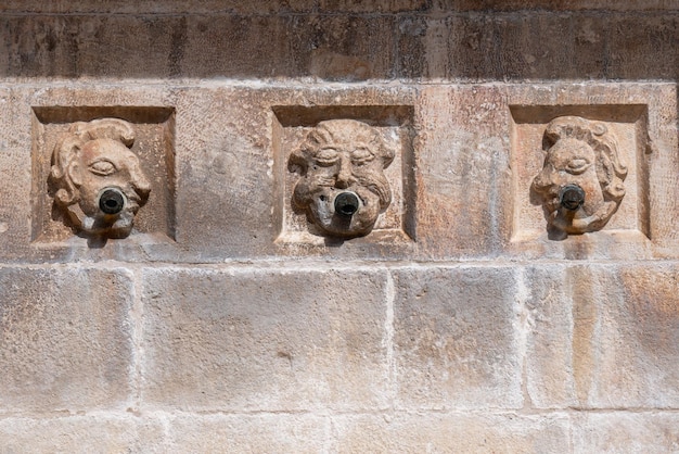 Três canos de água antigos em uma parede de pedra representando qiq