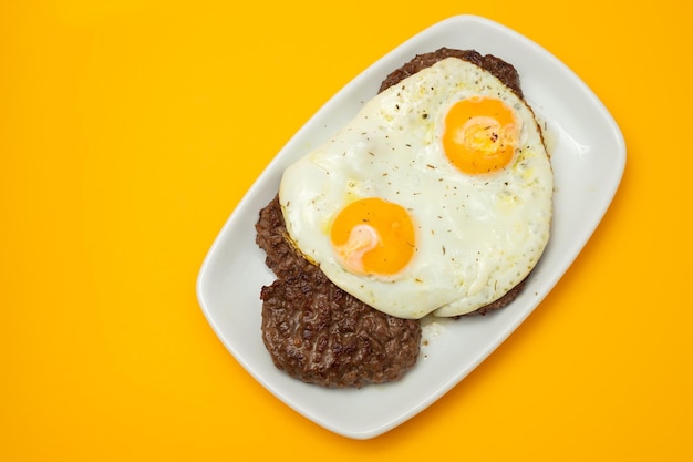 Tres carnes molidas fritas con huevo frito en un plato blanco