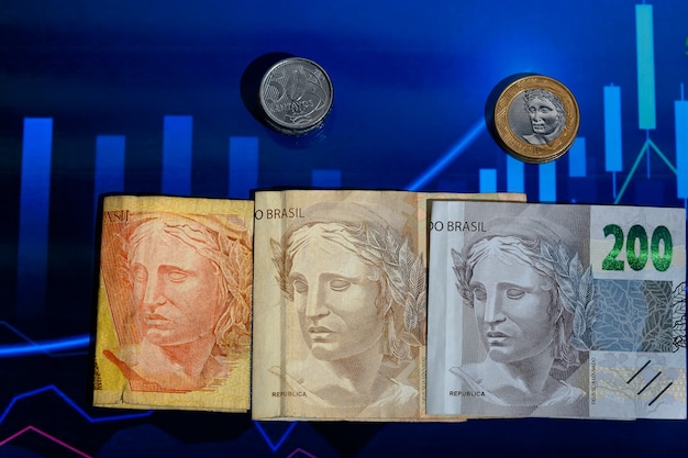 Foto tres cédulas de dinero brasileño con la imagen de la efinge que representa el rostro de la economía brasileña fotografiada en un gráfico