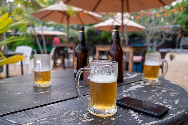 Tres cervezas en la mesa y el teléfono en la playa.