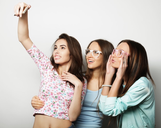 Foto tres chicas hipster adolescentes felices con smartphone tomando selfie