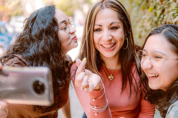 Tres chicas tomándose selfies en la calle luciendo felices porque se aman mucho
