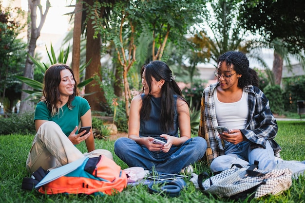 Tres chicas universitarias divirtiéndose mientras están sentadas en el césped