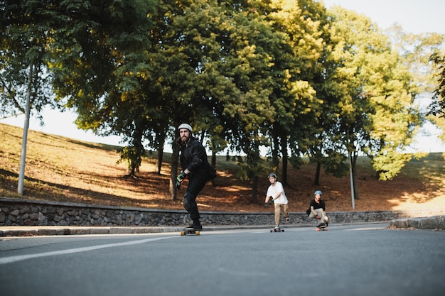 Tres chicos montan en longboard al atardecer. Foto de alta calidad