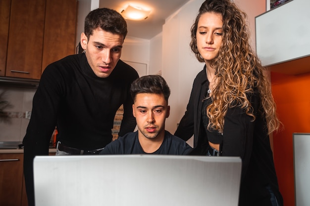 Tres chicos reunidos frente a una computadora portátil