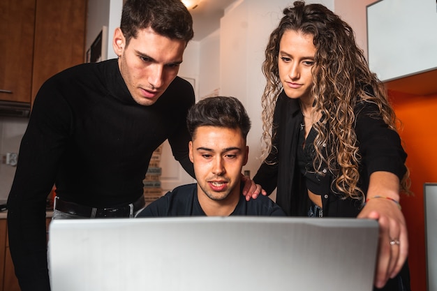 Tres chicos reunidos frente a una computadora portátil