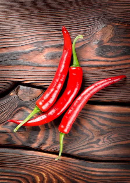 Tres chiles rojos sobre un fondo de madera