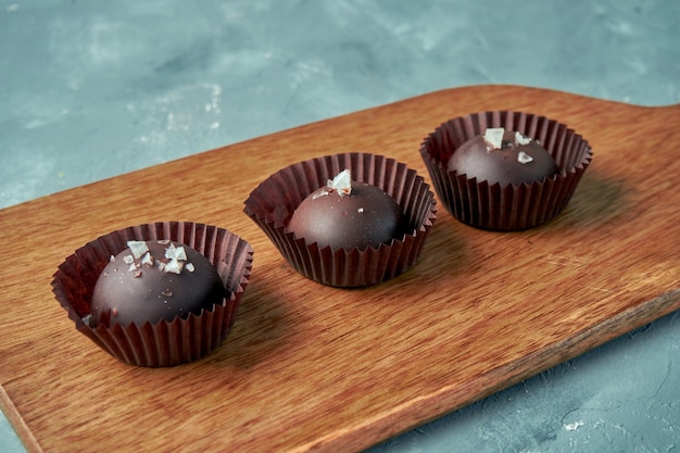 Tres chocolates rellenos con caramelo salado sobre una tabla de madera