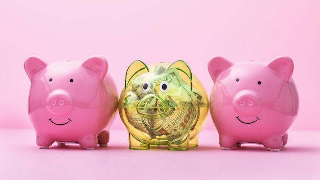Três cofrinhos em um fundo rosa, o conceito de investir em dólar