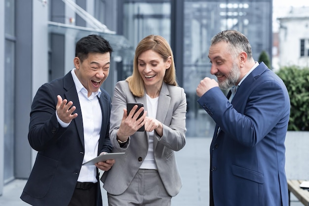 Tres colegas empleados ven videos divertidos o miran fotos recuerdos mirando