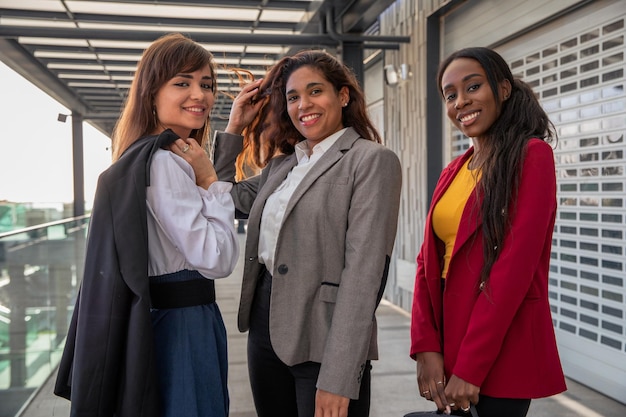 Três colegas sorridentes deixam os escritórios no final do dia de trabalho