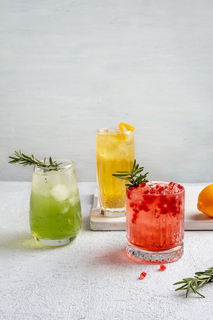 Tres coloridos cócteles de verano en vasos de mesa blanca. Surtido de bebidas frescas de verano.