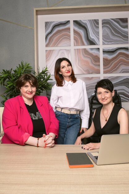 Foto tres compañeras de negocios sonríen y miran a la cámara retrato de compañeras de mediana edad mujeres empresarias exitosas