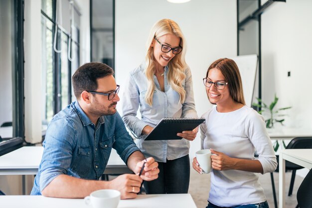 Tres compañeros de trabajo que se inspiran durante proceso de trabajo en oficina moderna.