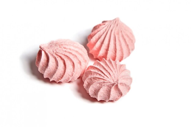 Três cookies de merengue. Merengues beijos na cor rosa, isolados no fundo branco