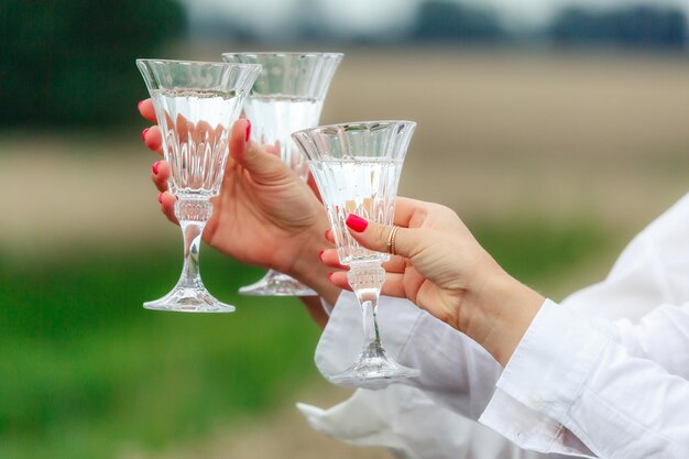 Tres copas grandes de vino blanco en manos femeninas closeup Celebrando un evento o cumpleaños Amigos de la boda brindan con champán