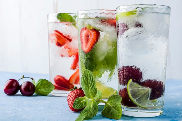 Três copos de bebida desintoxicante refrescante com morango, limão, cereja e hortelã