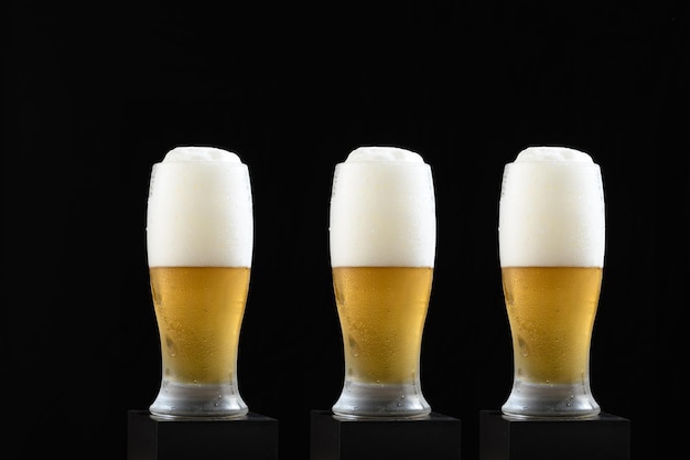 Três copos de cerveja com espuma no topo