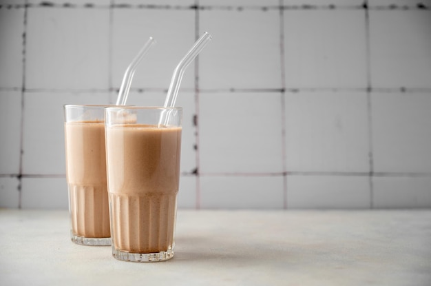 Três copos de milk-shake de chocolate com canudos em uma mesa.