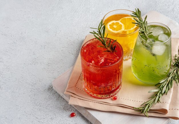 Três coquetéis coloridos de verão em copos na mesa branca. Variedade de bebidas frescas de verão.