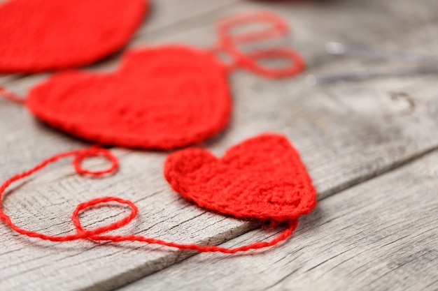 Três corações de malha vermelho, simbolizando o amor e a família. Relacionamento familiar, vínculos.