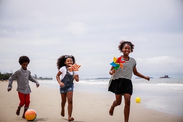 Três crianças afro-americanas se divertindo em uma praia tropical Conceito etnicamente diverso